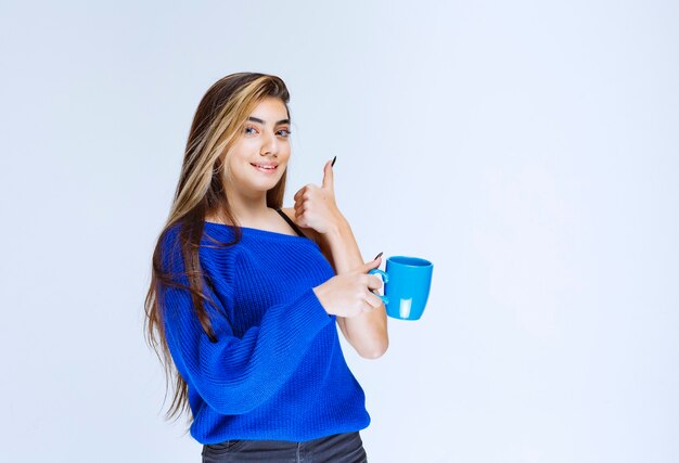 Chica tomando una taza de café y disfrutando del sabor.