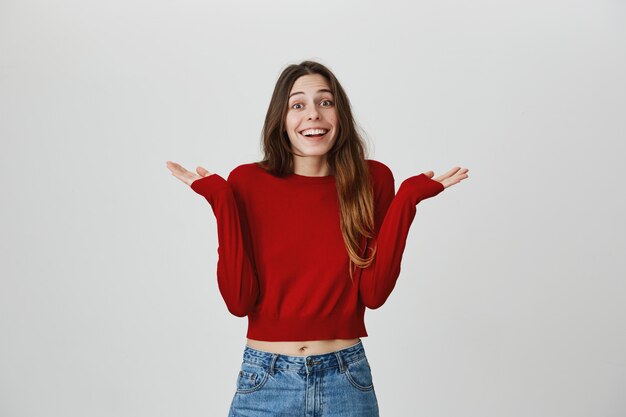 Chica tonta despistada con hermosa sonrisa encogiéndose de hombros sin darse cuenta