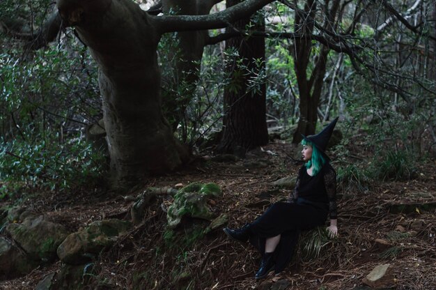 Chica en traje de bruja en el bosque