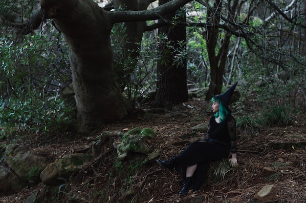 Chica en traje de bruja en el bosque