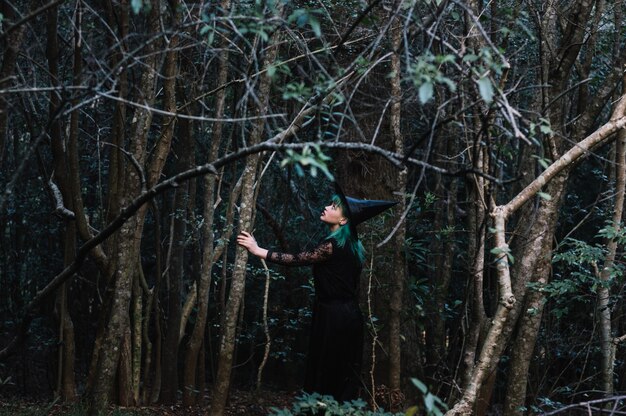 Chica en traje de bruja en el bosque