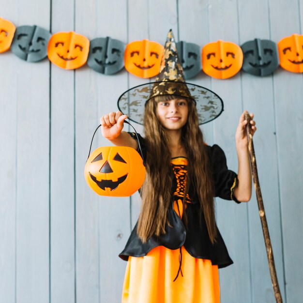 Chica en traje de bruja con cesta de Halloween