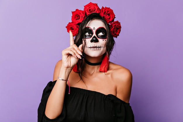 A una chica en traje de carnaval se le ocurrió una idea divertida. Retrato de mujer con rosas en cabello oscuro.