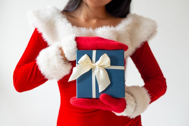 Chica en traje de santa mostrando caja de regalo