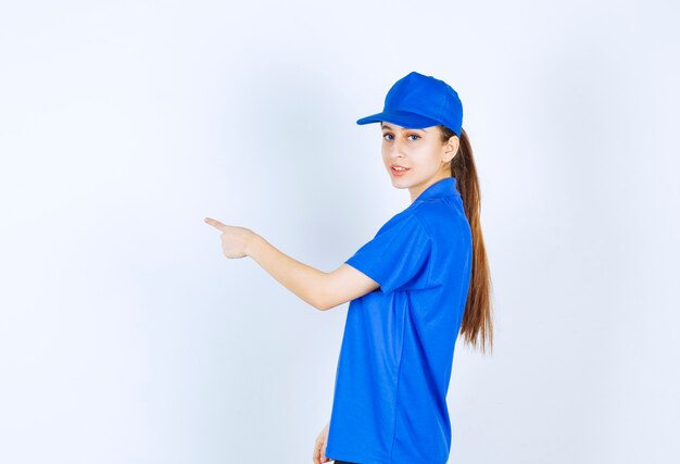 Chica en uniforme azul apuntando hacia el lado izquierdo.
