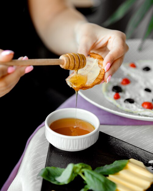 Chica unta miel sobre pan con mantequilla