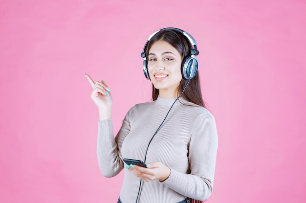 Chica usando audífonos y apuntando a algún lugar