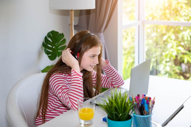 Chica usando computadora portátil en casa con auriculares