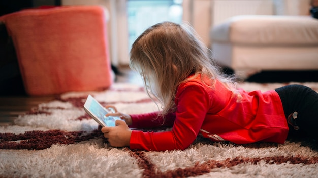 Foto gratuita chica usando tableta en la alfombra