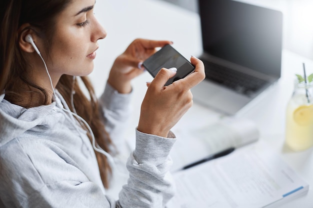 Foto gratuita chica usando un teléfono celular para disparar sus dibujos joven estudiante de caligrafía practicando en un gran espacio abierto escuchando música en tiempo real