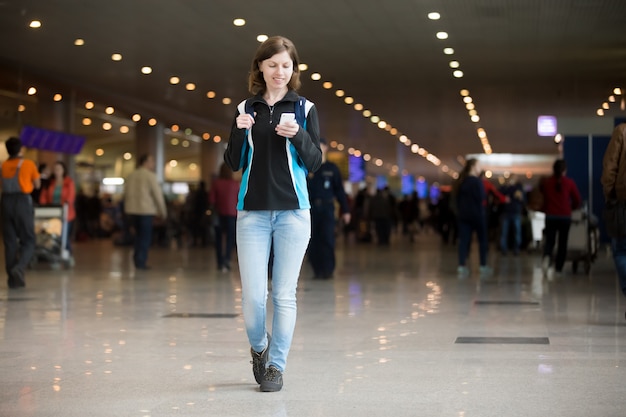 Chica utilizando teléfono celular en el aeropuerto