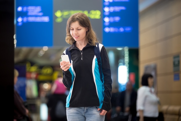 Chica utilizando teléfono móvil en el aeropuerto