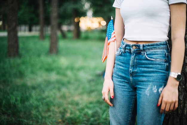 Chica con vaqueros y bandera americana en la naturaleza