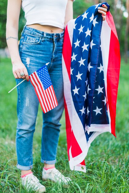 Chica con vaqueros y banderas americanas en la naturaleza