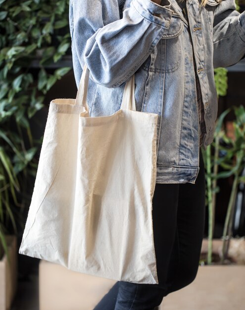 Chica vestida con chaqueta de mezclilla con bolsa ecológica
