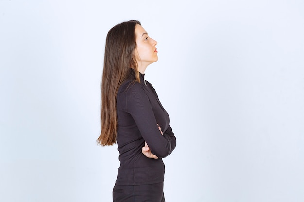 Chica vestida de negro dando poses profesionales y neutrales sin reacción.