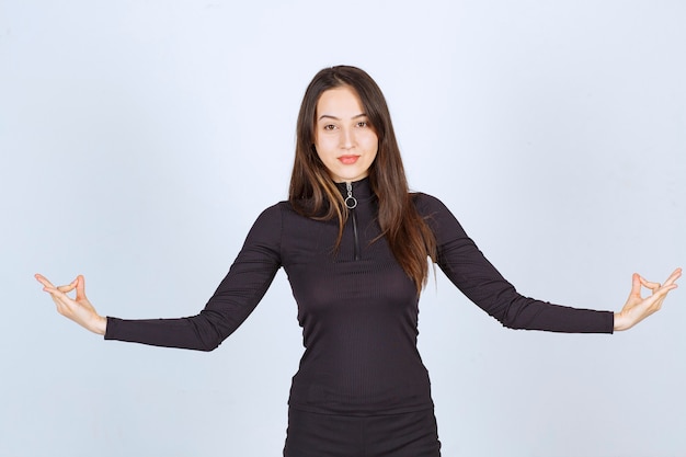 Chica vestida de negro haciendo meditación.