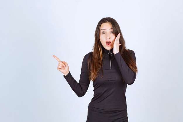 Chica vestida de negro mirando sorprendida y asustada.