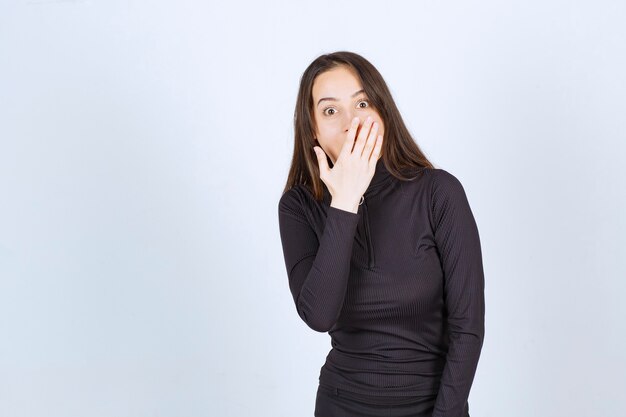 Chica vestida de negro mirando sorprendida y asustada.