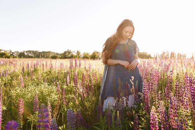 chica en vestido azul caminando en el campo de flores.