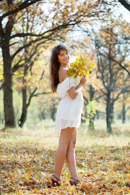 Chica en vestido blanco en otoño parque