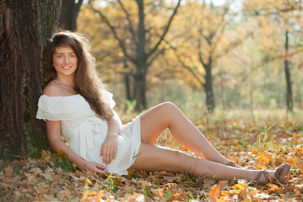 Chica en vestido blanco en otoño parque