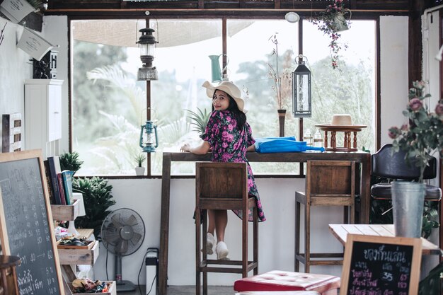 Chica con un vestido floral y con un sombrero sentado