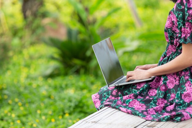 Chica con un vestido de flores sentado con su computadora portátil