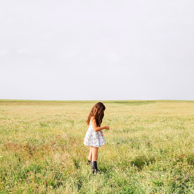 Chica en vestido lindo de pie en el campo