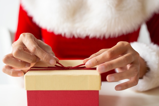 Chica en vestido de Navidad envolver regalo en la mesa