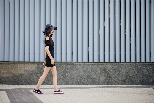 Chica en vestido negro caminando fuera