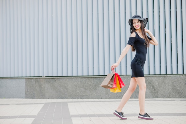 Chica en vestido negro caminando fuera