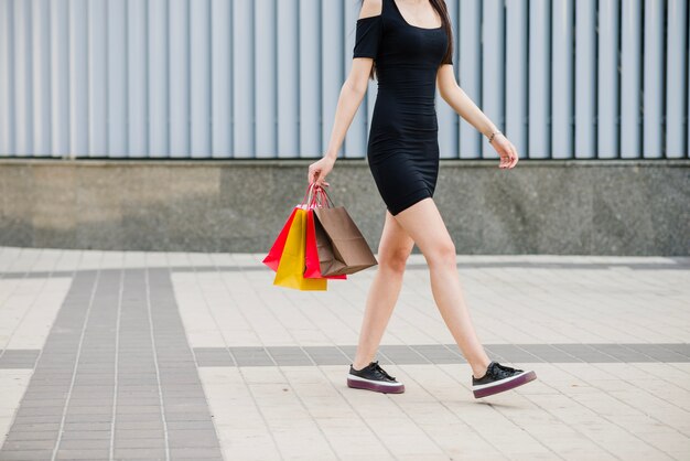 Chica en vestido negro caminando en el pavimento