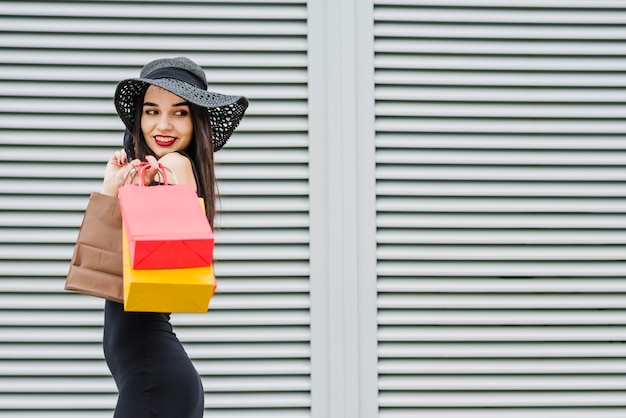 Chica en vestido negro llevando bolsas de la compra