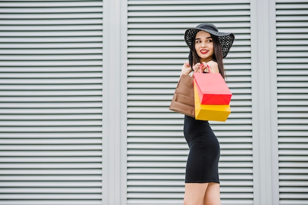 Chica en vestido negro llevando bolsas de la compra