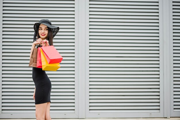 Chica en vestido negro llevando bolsas de la compra