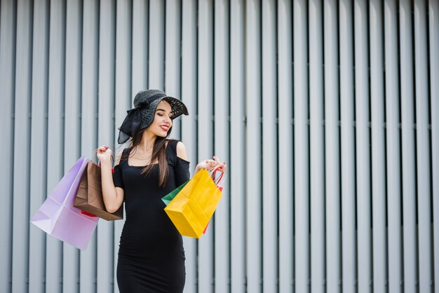 Chica en vestido negro llevando bolsas de la compra