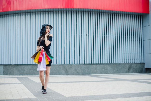 Chica en vestido negro llevando bolsas de la compra