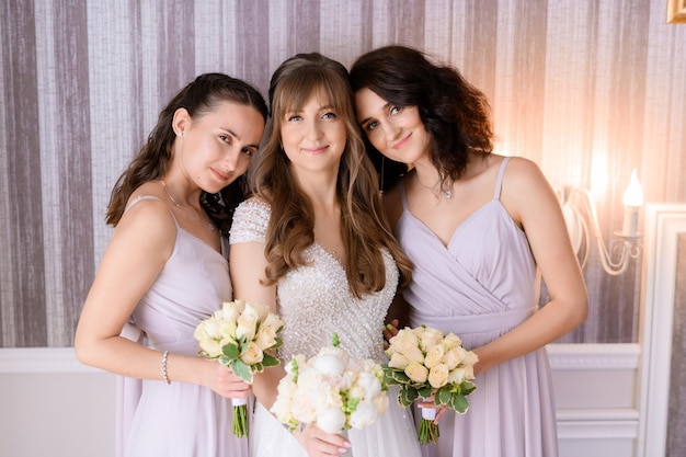 Chica en vestido de novia de pie con damas de honor interior