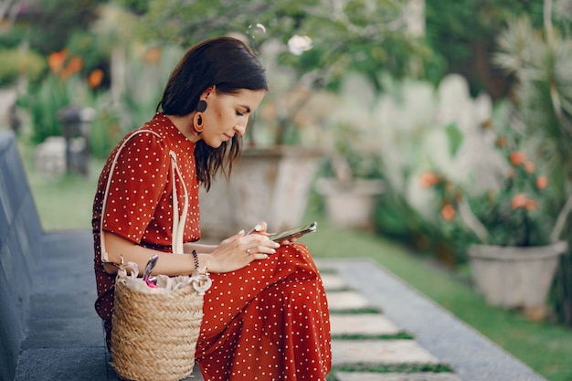 Chica en un vestido rojo sentado y usa el teléfono