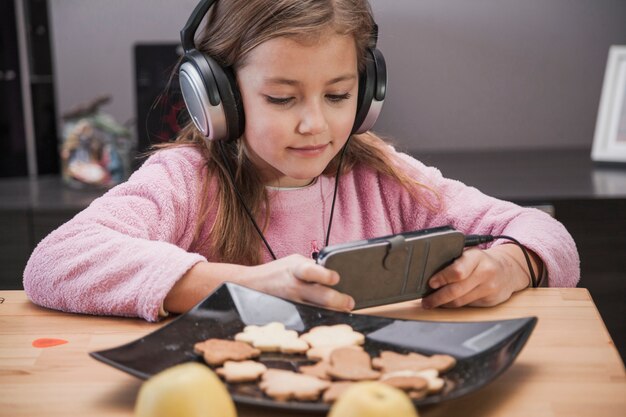 Chica viendo el teléfono inteligente en la mesa