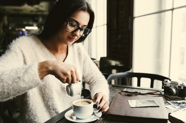 Chica vierte leche en una taza de café