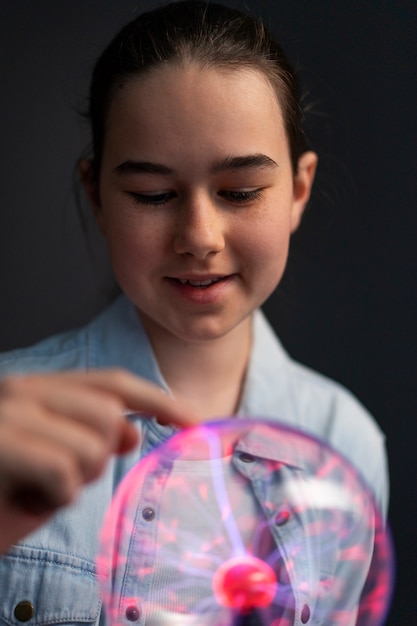 Chica de vista frontal interactuando con una bola de plasma