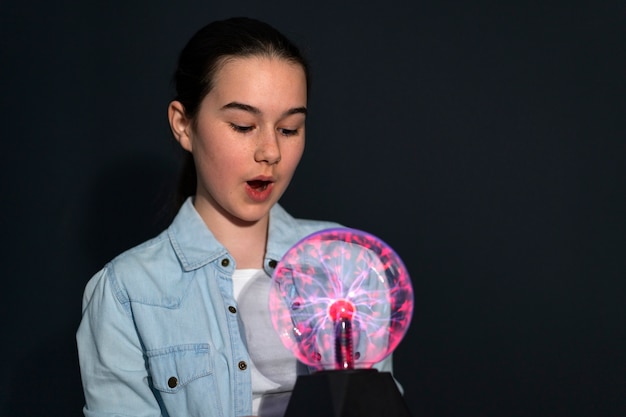 Chica de vista frontal interactuando con una bola de plasma