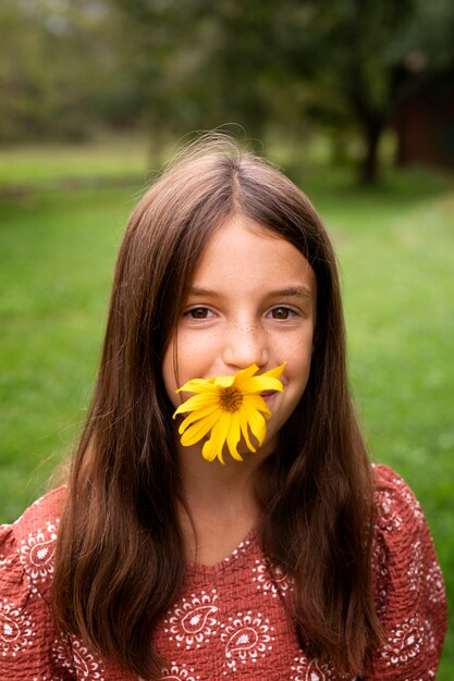 Chica de vista frontal posando con flor