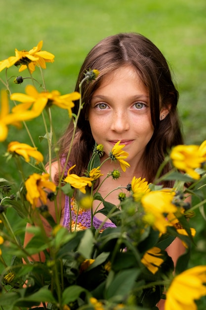 Foto gratuita chica de vista frontal posando con flores