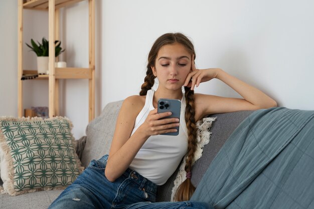 Chica de vista frontal en el sofá con teléfono inteligente