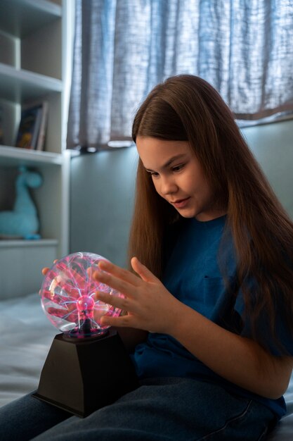 Chica de vista lateral interactuando con una bola de plasma