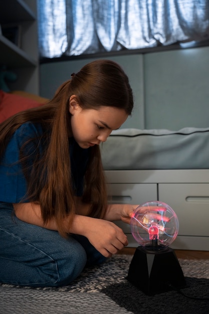 Chica de vista lateral interactuando con una bola de plasma