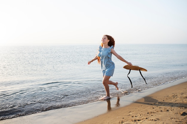 Foto gratuita chica de vista lateral en la playa con sombrero